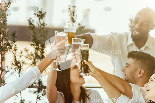 Image of Young group of friends drinking beer and celebrating together