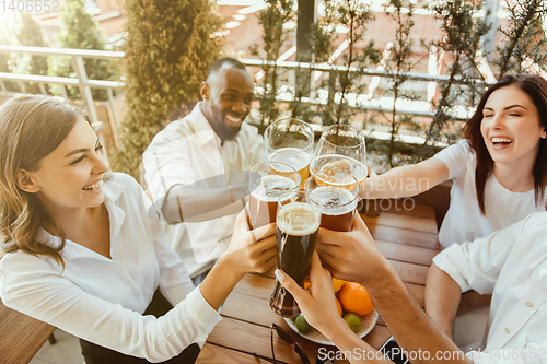 Image of Young group of friends drinking beer and celebrating together