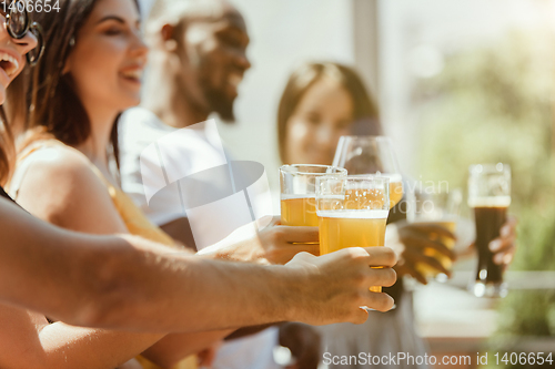 Image of Young group of friends drinking beer and celebrating together