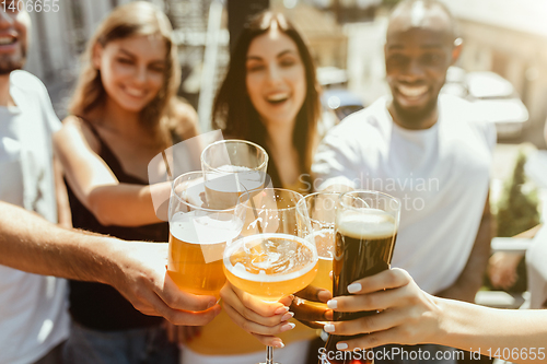 Image of Young group of friends drinking beer and celebrating together