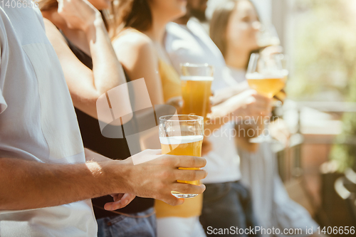 Image of Young group of friends drinking beer and celebrating together