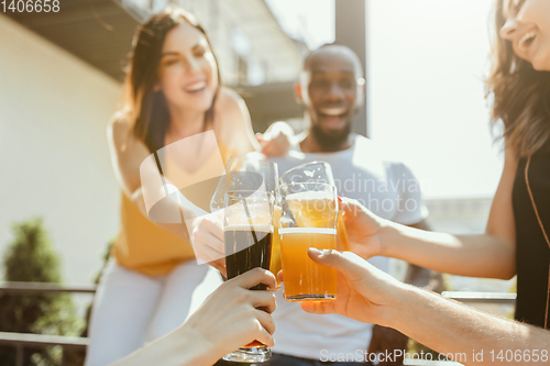 Image of Young group of friends drinking beer and celebrating together