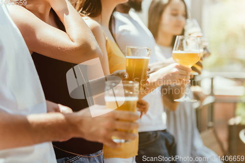 Image of Young group of friends drinking beer and celebrating together