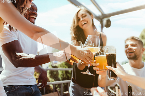 Image of Young group of friends drinking beer and celebrating together