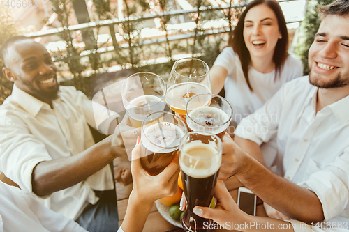 Image of Young group of friends drinking beer and celebrating together