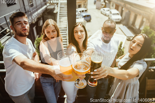 Image of Young group of friends drinking beer and celebrating together