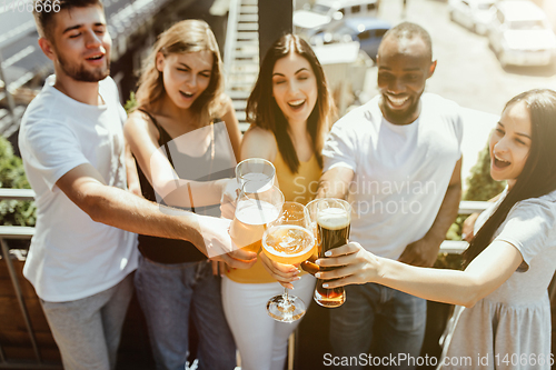 Image of Young group of friends drinking beer and celebrating together