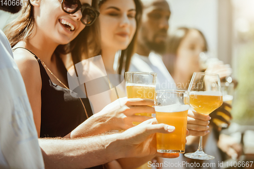 Image of Young group of friends drinking beer and celebrating together