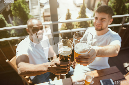 Image of Young group of friends drinking beer and celebrating together