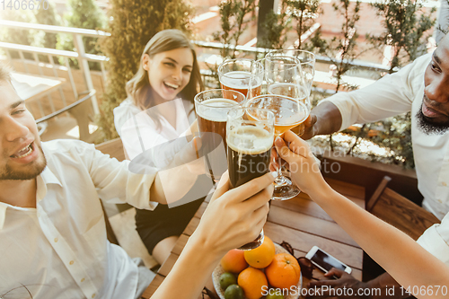 Image of Young group of friends drinking beer and celebrating together