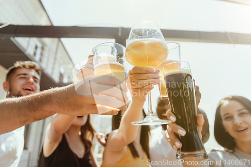 Image of Young group of friends drinking beer and celebrating together