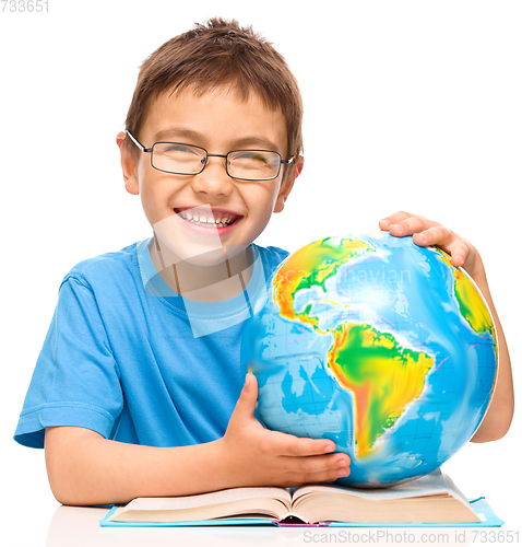 Image of Little boy is examining globe