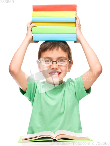 Image of Little boy is holding a pile of books