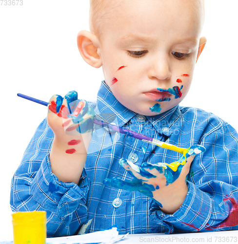 Image of Little boy is playing with paints