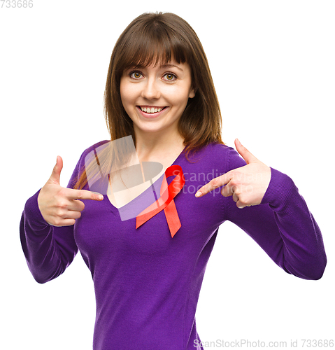 Image of Woman is pointing to the red awareness ribbon