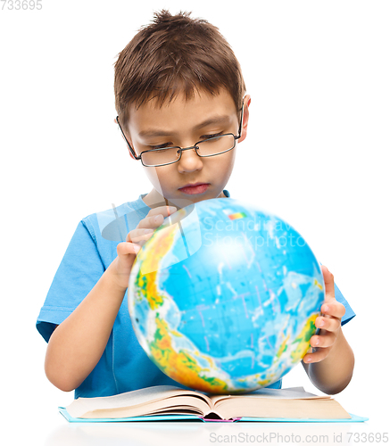 Image of Little boy is examining globe