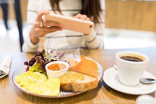 Image of Woman taking photo with cellphone in restaurant