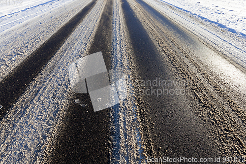 Image of part of the snow-covered asphalt road close up