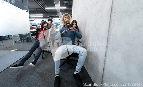 Image of multiethnics business team racing on office chairs