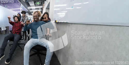 Image of multiethnics business team racing on office chairs