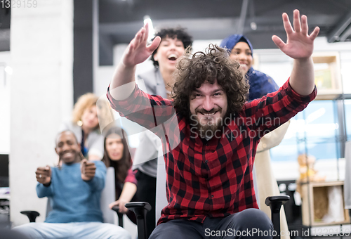 Image of multiethnics business team racing on office chairs