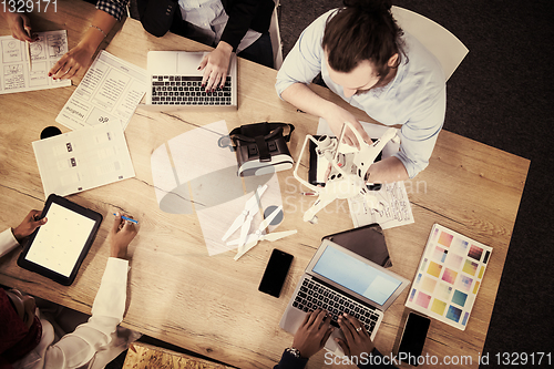 Image of top view of multiethnic business team learning about drone techn