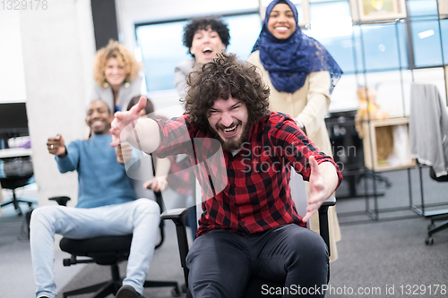 Image of multiethnics business team racing on office chairs