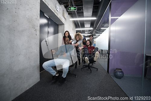 Image of multiethnics business team racing on office chairs