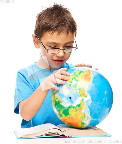 Image of Little boy is examining globe