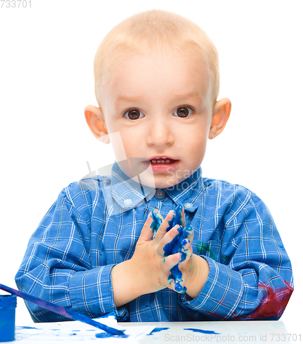 Image of Little boy is playing with paints