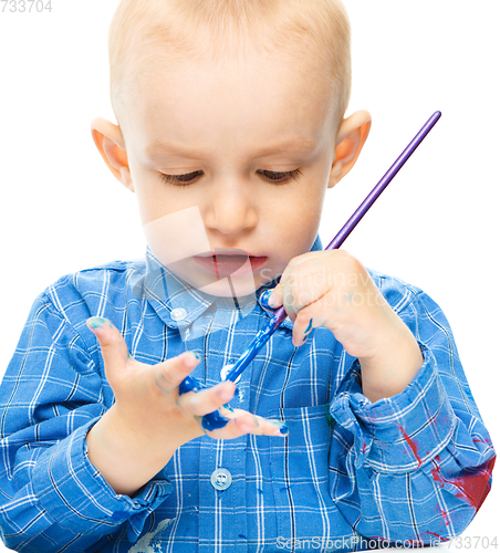 Image of Little boy is playing with paints