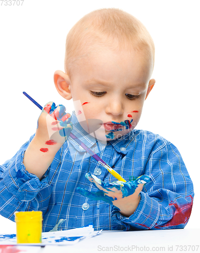 Image of Little boy is playing with paints