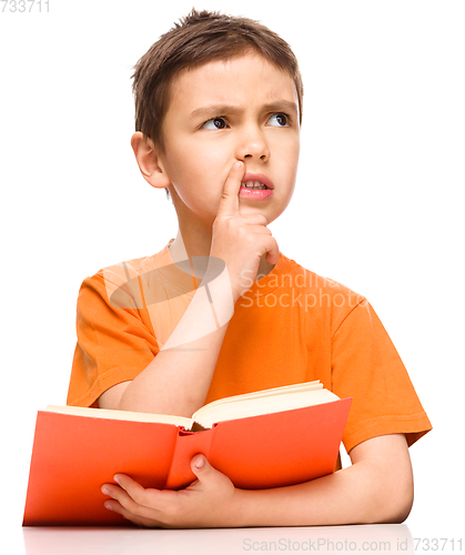 Image of Young boy is daydreaming while reading book