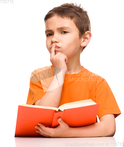 Image of Young boy is daydreaming while reading book