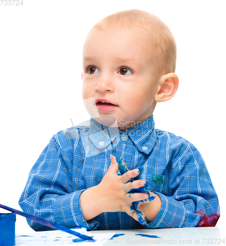 Image of Little boy is playing with paints