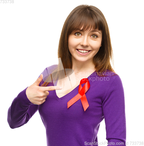 Image of Woman is pointing to the red awareness ribbon
