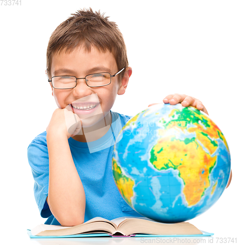 Image of Little boy is examining globe