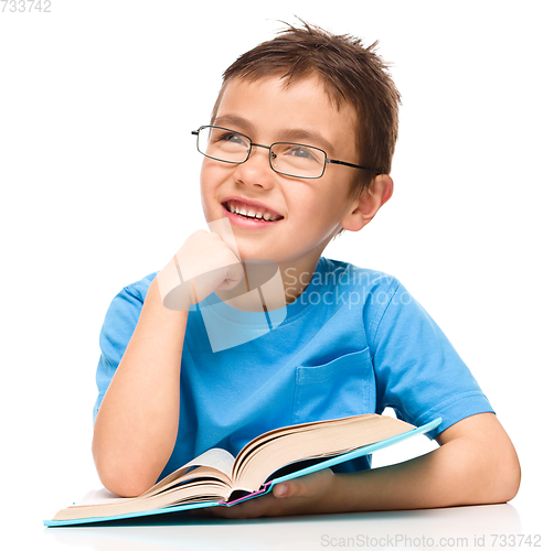 Image of Young boy is daydreaming while reading book