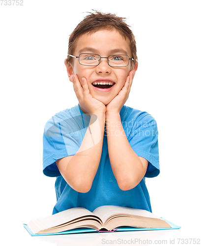 Image of Astonished little boy is reading a book