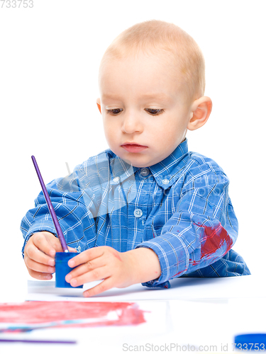 Image of Little boy is playing with paints