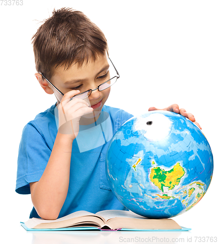 Image of Little boy is examining globe