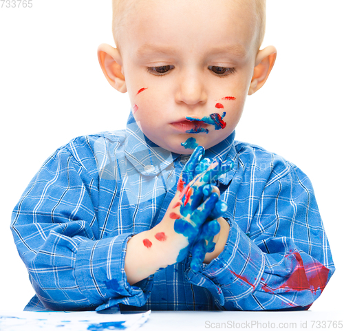 Image of Little boy is playing with paints
