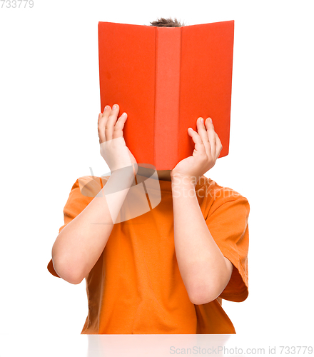 Image of Little boy is hiding behind a book