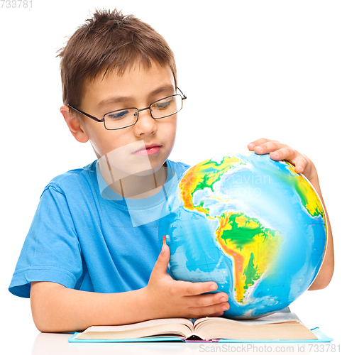 Image of Little boy is examining globe