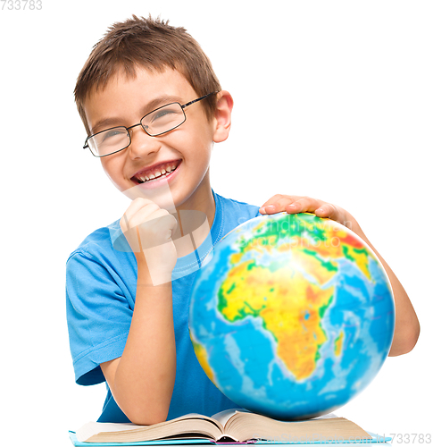 Image of Little boy is examining globe