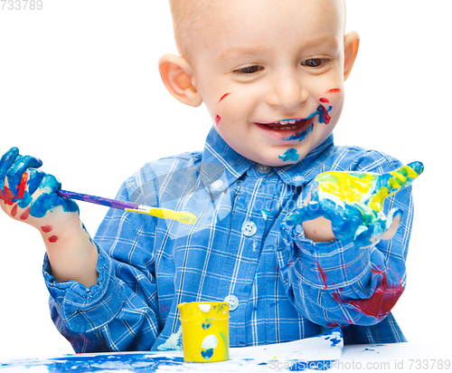 Image of Little boy is playing with paints