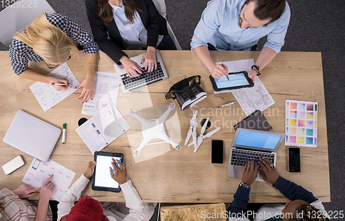 Image of top view of multiethnic business team learning about drone techn