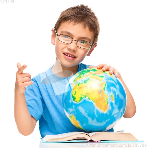 Image of Little boy is examining globe