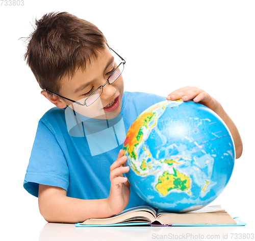 Image of Little boy is examining globe