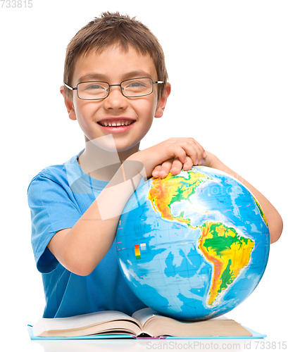 Image of Little boy is examining globe